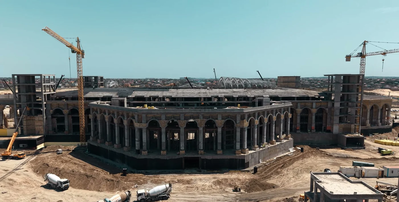 The colonnaded facade: tower cranes and concrete mixers